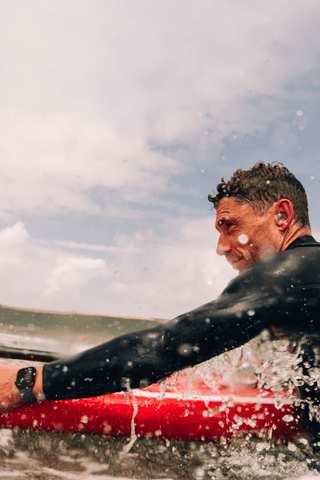 Ein Mann mit einem Paddle Board im Wasser, der eine Apple Watch Series 10 trägt.